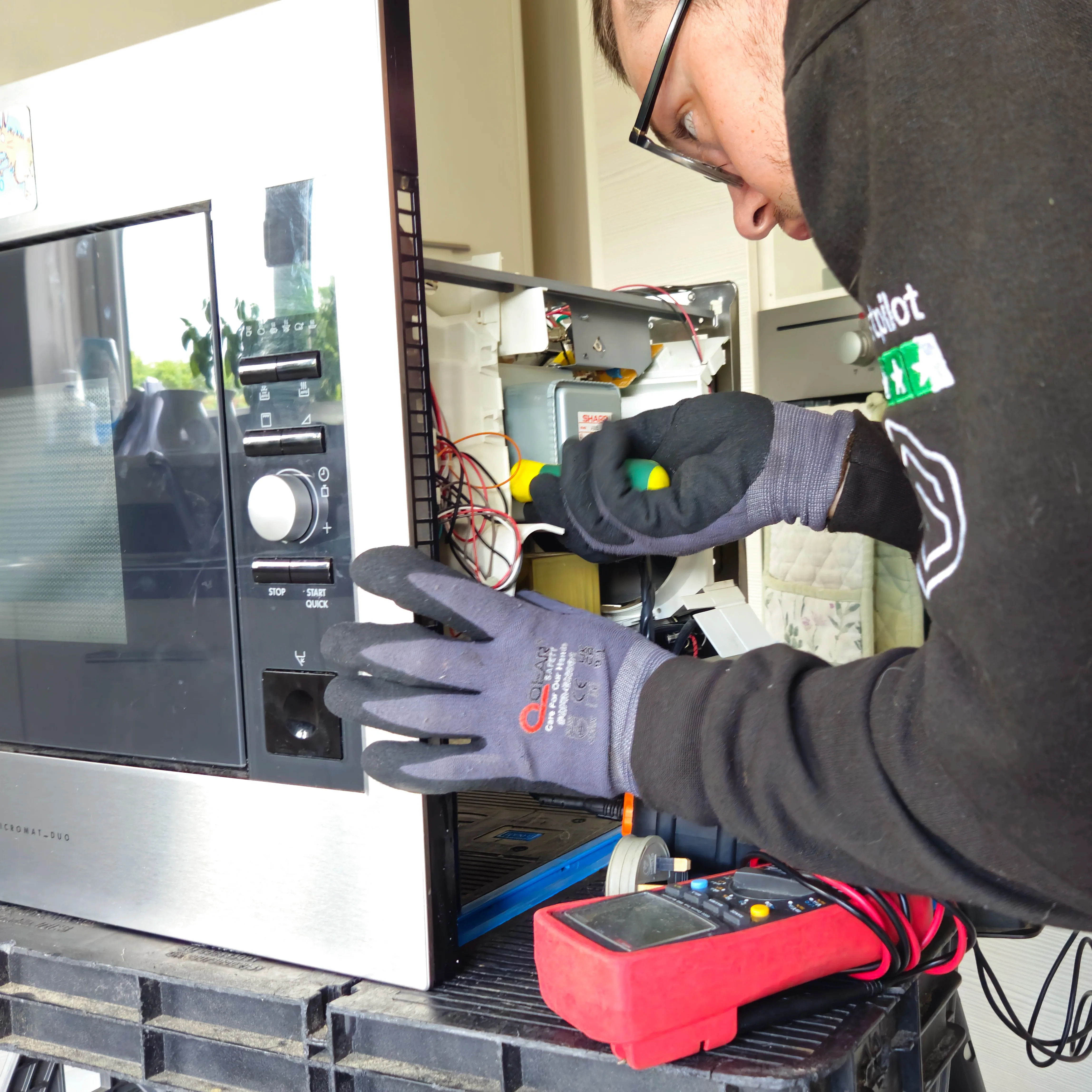 A NAC engineer testing and repairing a microwave in a customer's home